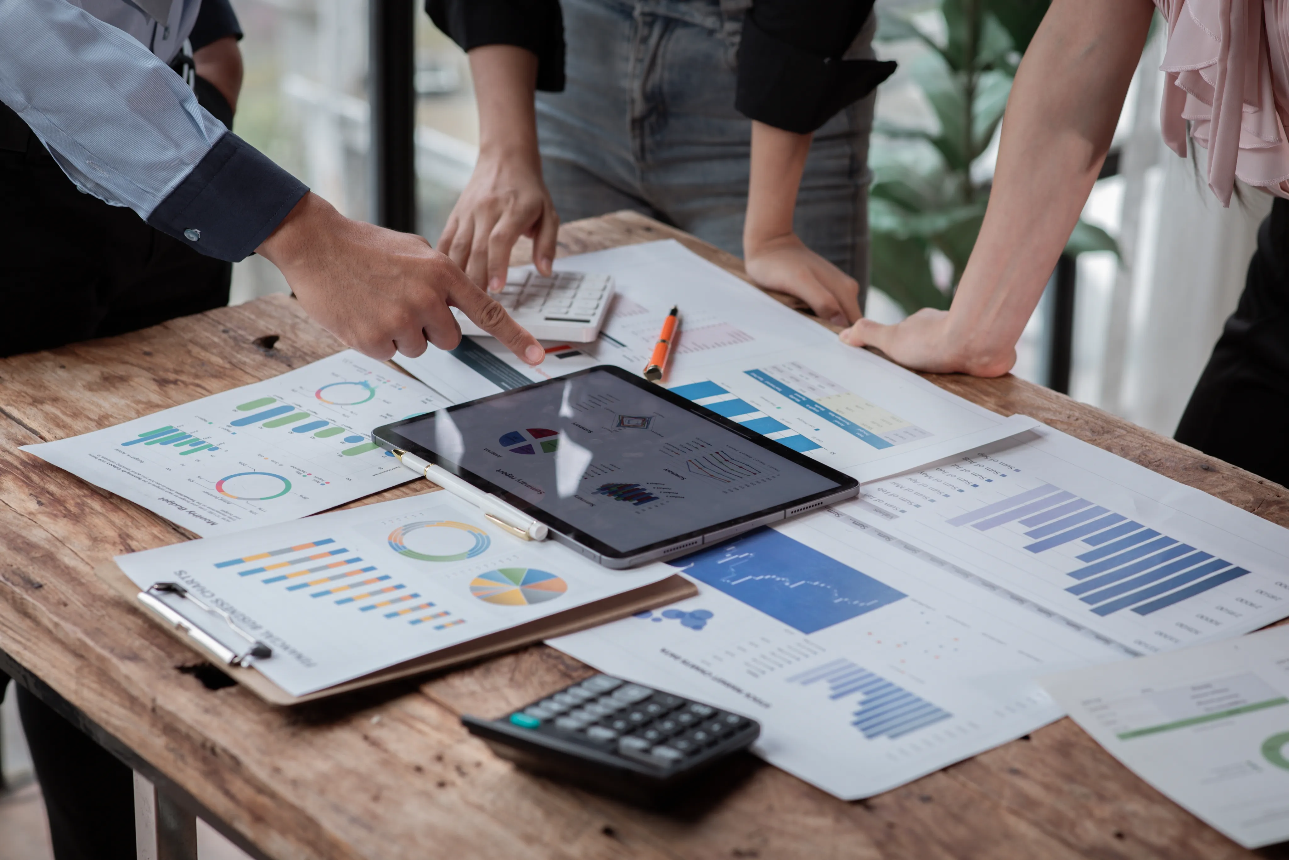 Ein Team von Personen, das Finanzdiagramme auf einem Tablet und auf Papier überprüft.